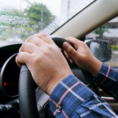 A pair of hands on a car steering wheel. 